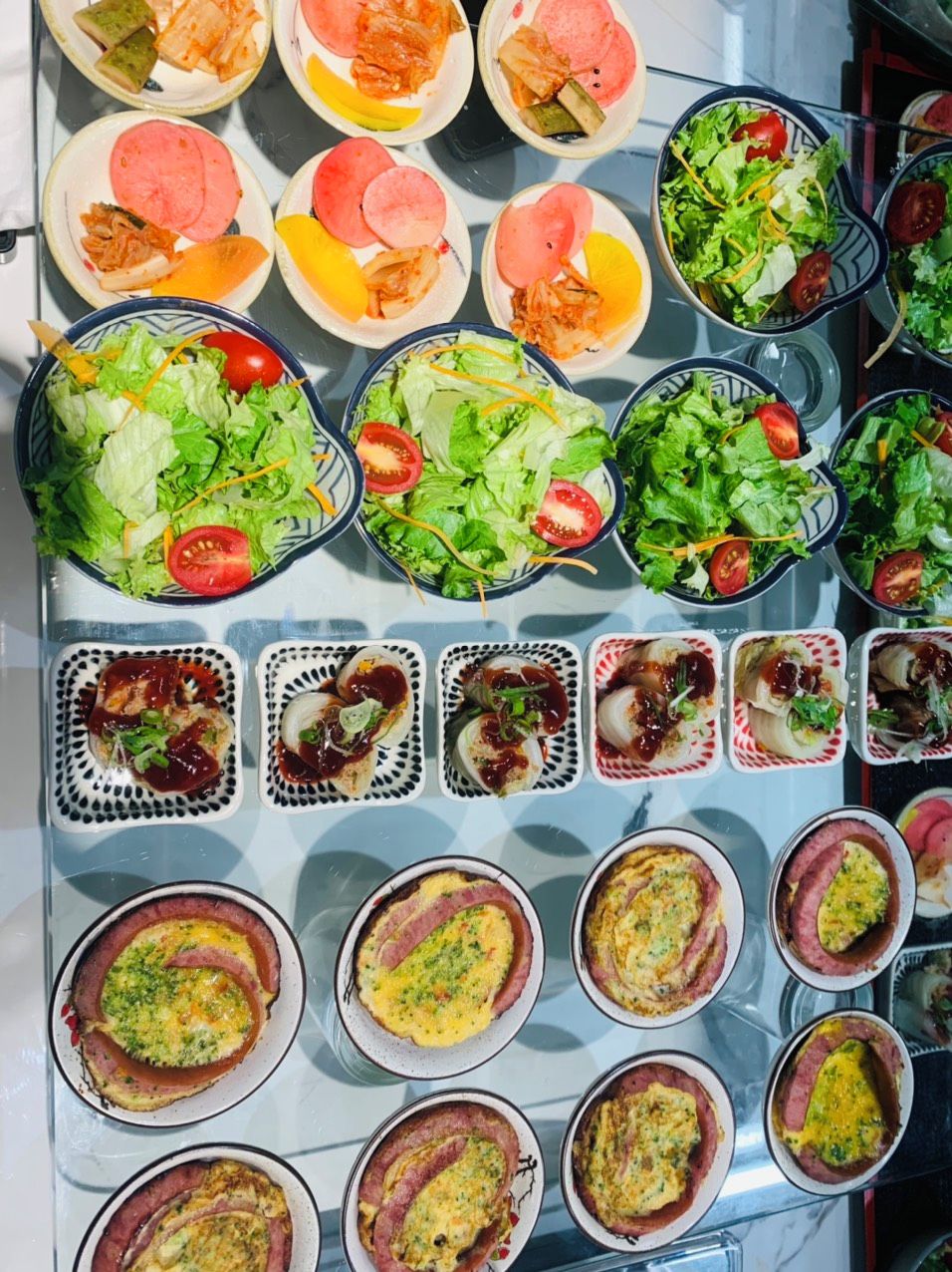 Buffet com diversos pratos, incluindo saladas, sanduíches e omeletes.