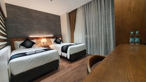 Ein Hotelzimmer mit zwei Betten, einem Holztisch und einem Stuhl.