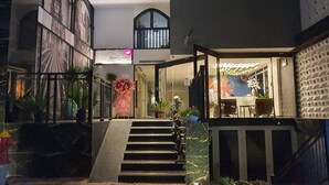 Eine Hotelhalle mit einer Treppe zu einer zweiten Etage, einem Empfangstresen und einer dekorativen Blumenkomposition.