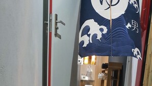 Ein Flur mit einer Reihe von Laternen auf einem Kiesweg, der zu einem Raum mit Wand im japanischen Stil führt.