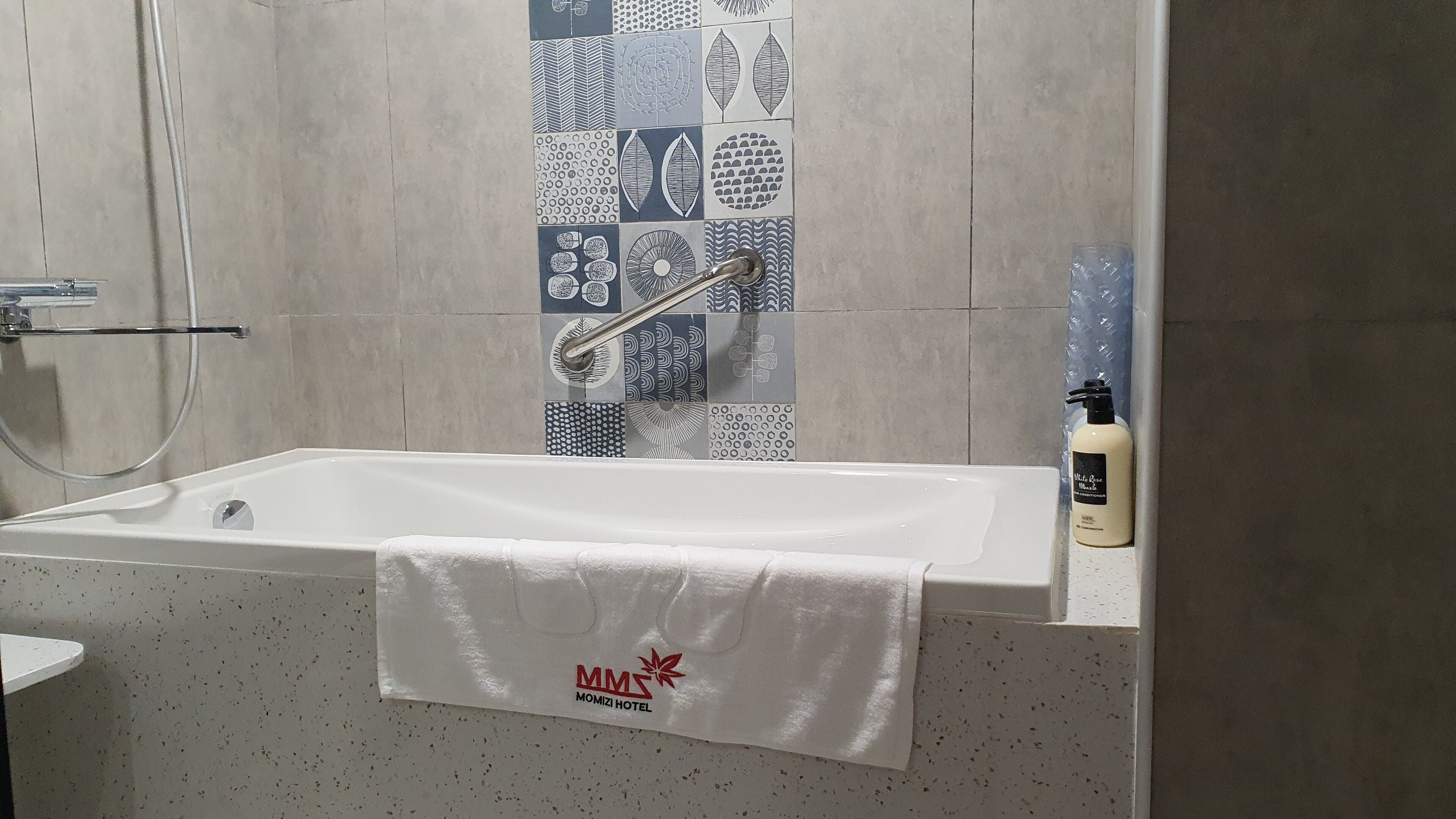 A bathroom with a white bathtub, a towel hanging on the side, and a shower area.