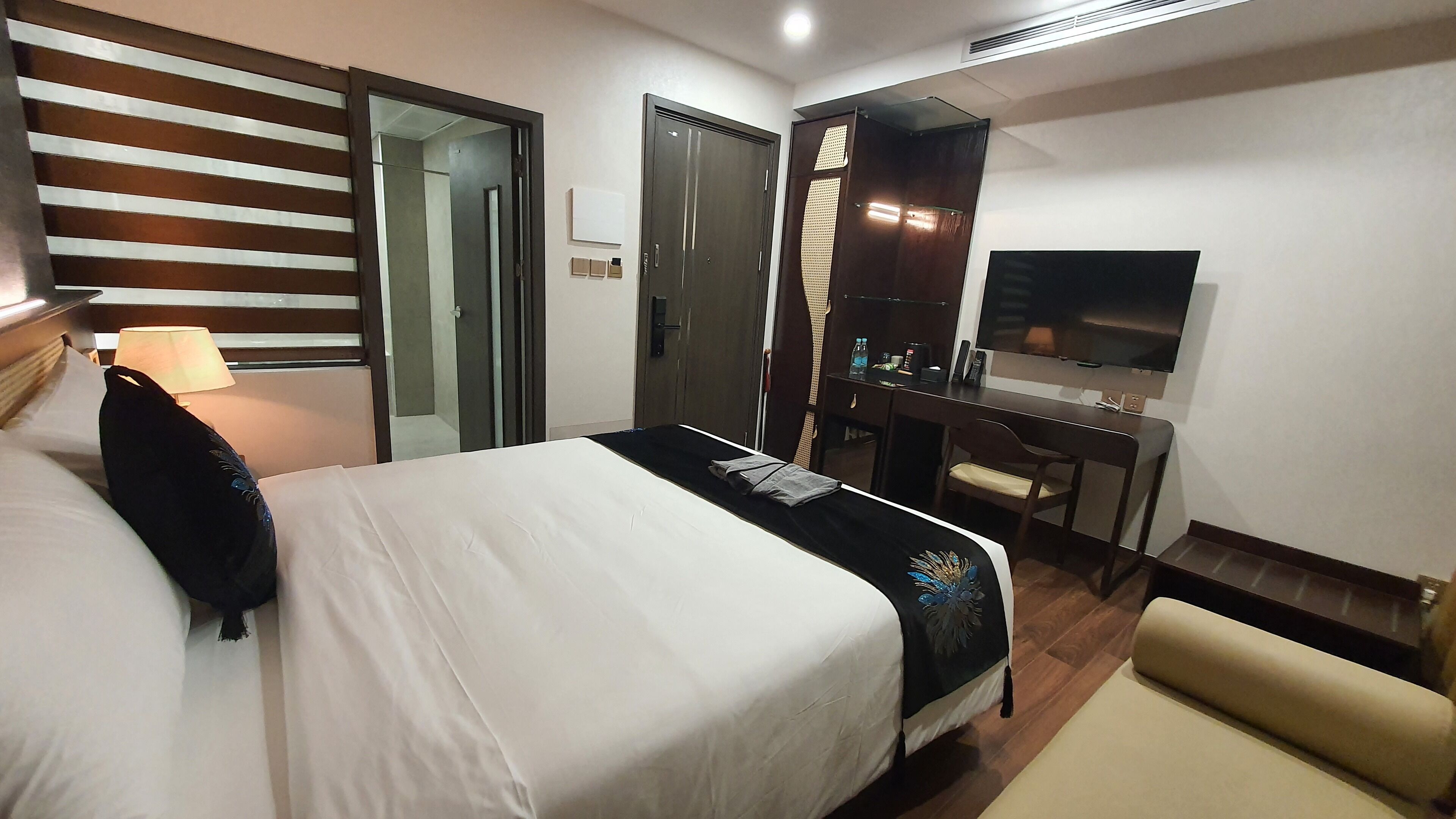 Une chambre d’hôtel équipée d’un lit, d’un bureau, d’une chaise, d’une télévision et d’un miroir.