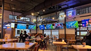 Un restaurant doté de plusieurs écrans diffusant des programmes sportifs, de tables en bois et offrant une ambiance décontractée.