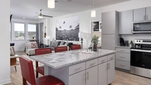 Una cocina moderna con gabinetes grises, encimera de granito y electrodomésticos de acero inoxidable.