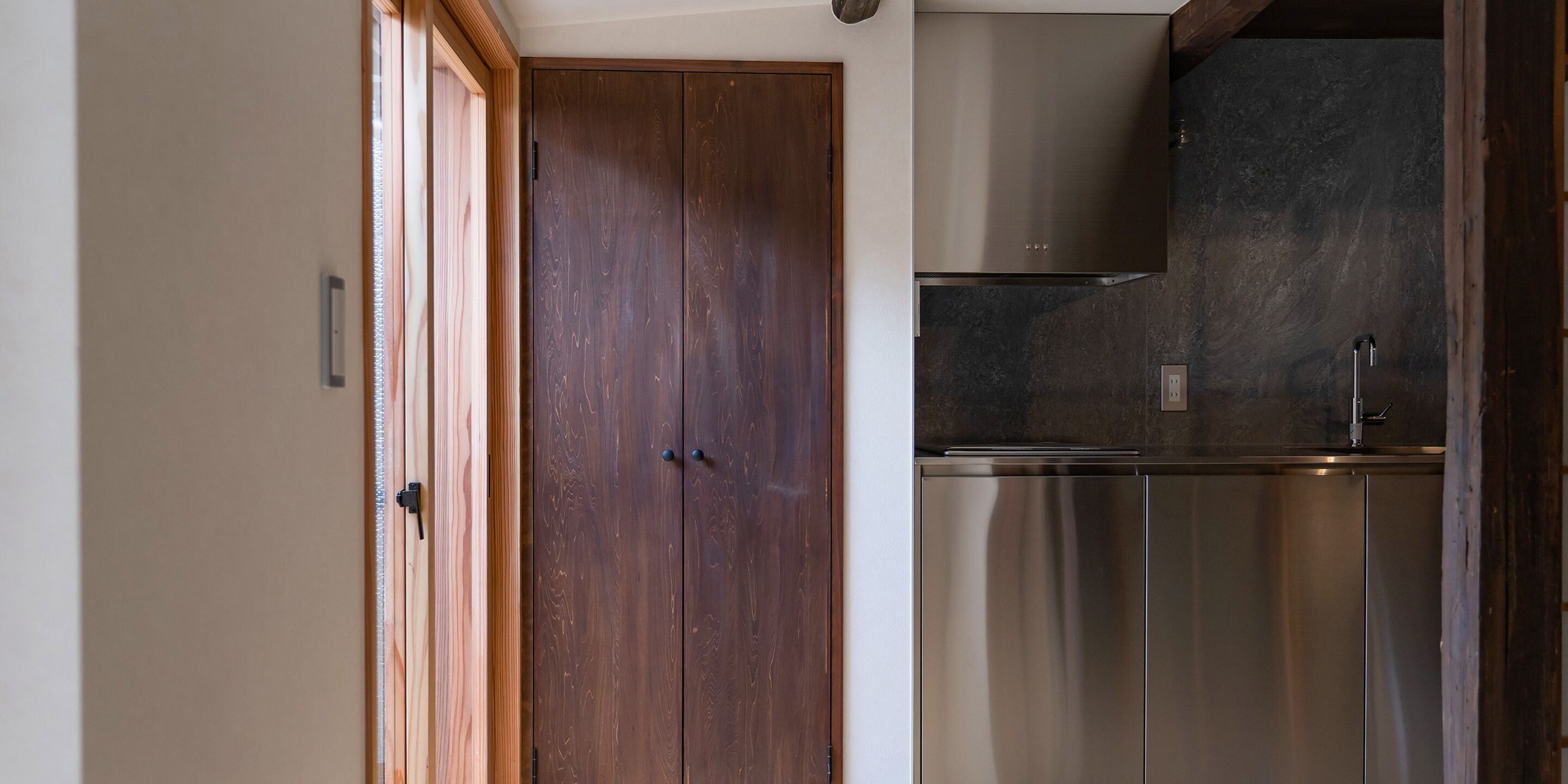 Une cuisine moderne dotée d’un réfrigérateur en acier inoxydable, de meubles en bois et d’un four encastré.