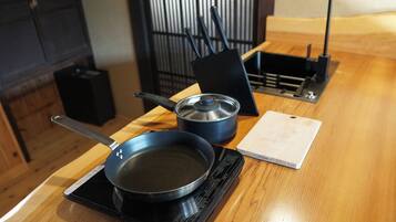 Een keuken met een fornuis, een koekenpan, een pan en een snijplank op een houten tafel.