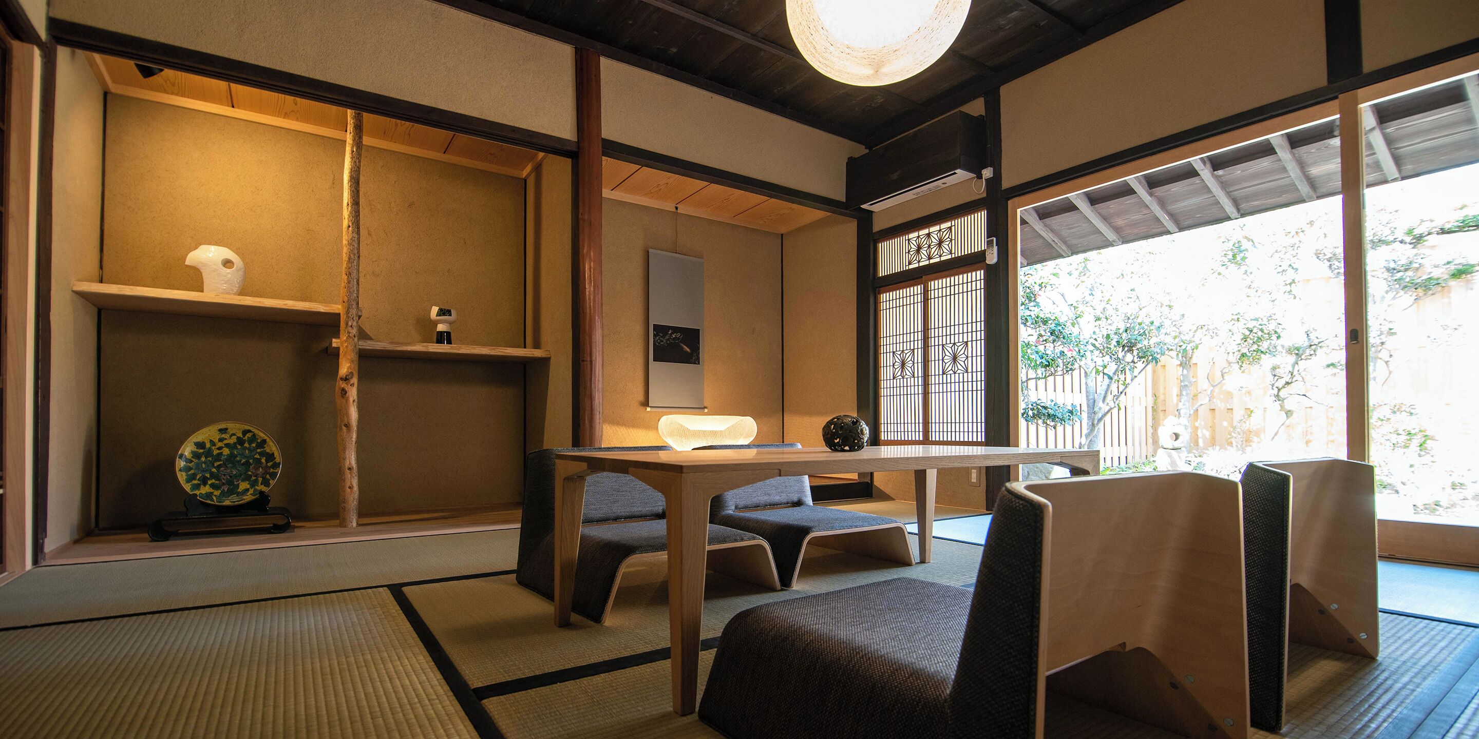 A traditional Japanese room with tatami flooring, a low table, and seating.