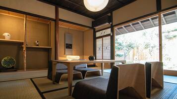 A traditional Japanese room with tatami flooring, a low table, and seating.