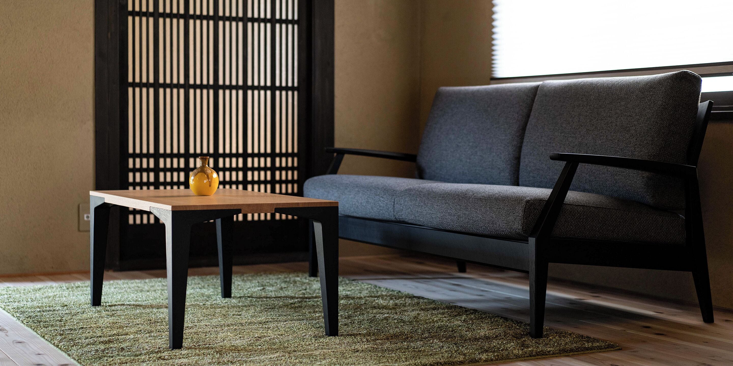 A modern living room with a grey sofa, a wooden coffee table, and a patterned rug.