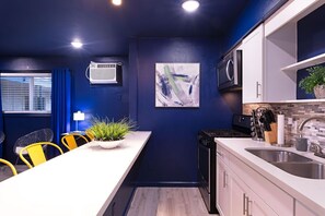 Enjoy cooking in this well-equipped kitchen with a stove, microwave, and sink, plus a dining area with chairs and a table.