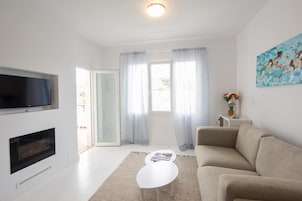 Una sala de estar moderna con televisor de pantalla plana, chimenea, sofá y una mesita de centro.