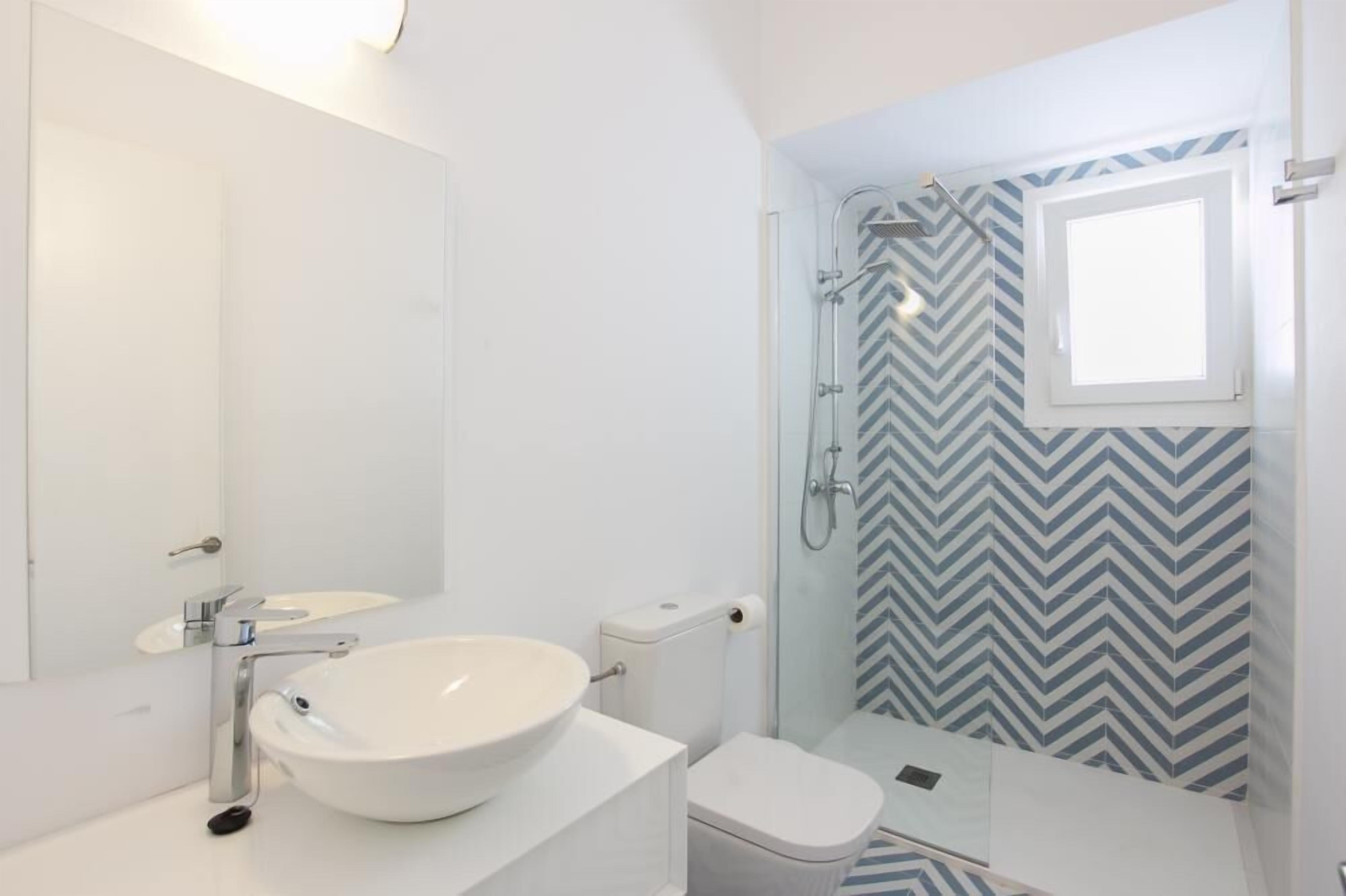 A modern bathroom with a white sink, toilet, and shower.