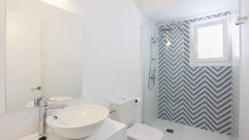 Un bany modern amb un lavabo, un vàter i una dutxa de color blanc.