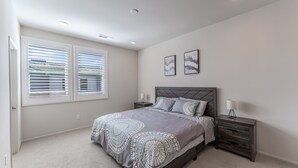A bedroom with a bed, two bedside tables, a nightstand, a window with blinds, and two wall-mounted pictures. - Brand New 3b3b Condo in the heart of West Covina (West Covina)