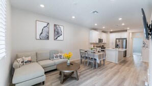 A modern living room with a sofa, a coffee table, and a dining area with chairs and a table. - Brand New 3b3b Condo in the heart of West Covina (West Covina)