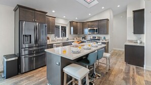 A modern kitchen with stainless steel appliances, a central island, and a skylight. - Large Groups, Volleyball Court, Large Space (Flagstaff)