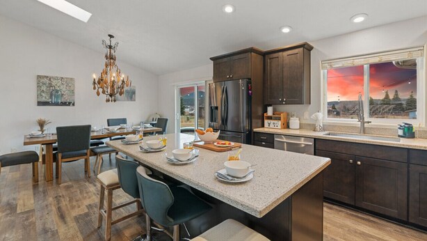 A modern kitchen with a central island, dark cabinetry, and a large window with a sunset view. - Large Groups, Volleyball Court, Large Space (Flagstaff)