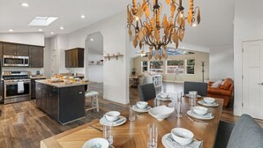 A modern kitchen with a central island, dining area with a chandelier, and a living room with a sofa. - Large Groups, Volleyball Court, Large Space (Flagstaff)