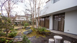 A modern building with a stone pathway leading to a seating area with three stools. - HOTEL DO-YA BEPPU Hanare (Beppu)