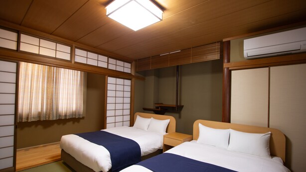 A traditional Japanese-style hotel room with two beds, tatami flooring, shoji screens, and a ceiling fan. - HOTEL DO-YA BEPPU Hanare (Beppu)