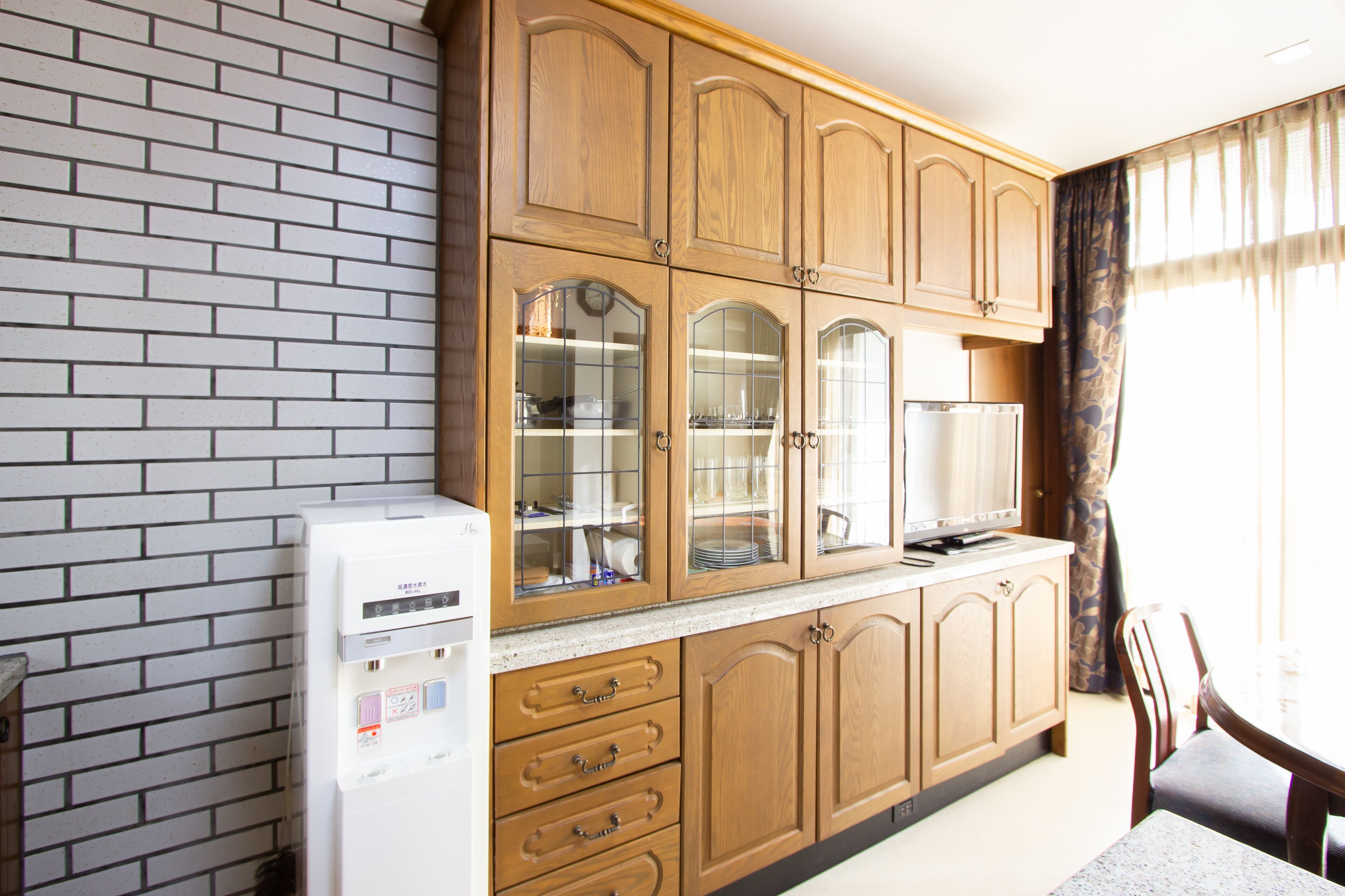 Una cocina con armarios de madera, un refrigerador y una zona de comedor con una mesa y sillas.