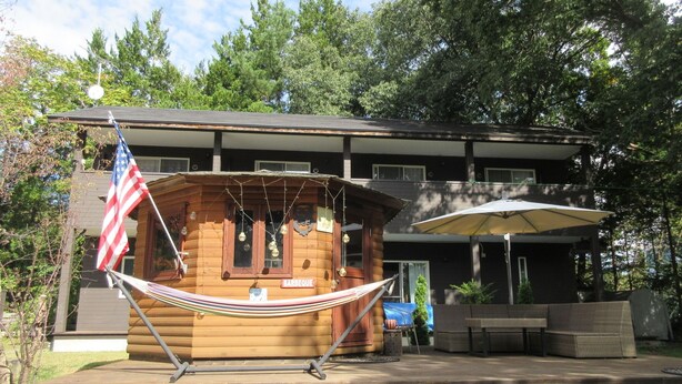 Eine Holzhütte mit einer Hängematte, einem Grillschild und einer amerikanischen Flagge.