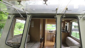 Ein Campervan-Innenraum mit zwei Schlafbereichen, einer Küchenzeile und einem kleinen Badezimmer.