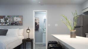 Ein modernes Schlafzimmer mit Bett, Nachttisch, Lampe und einem Blumentopf.