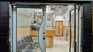 A hotel entrance with a reception desk, a waiting area with chairs, and a potted plant. - Hotel Dinar (Kolkata)