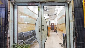 A double door entrance with a mirrored design, leading into a hallway with a tiled floor and a potted plant. - Hotel Dinar (Kolkata)