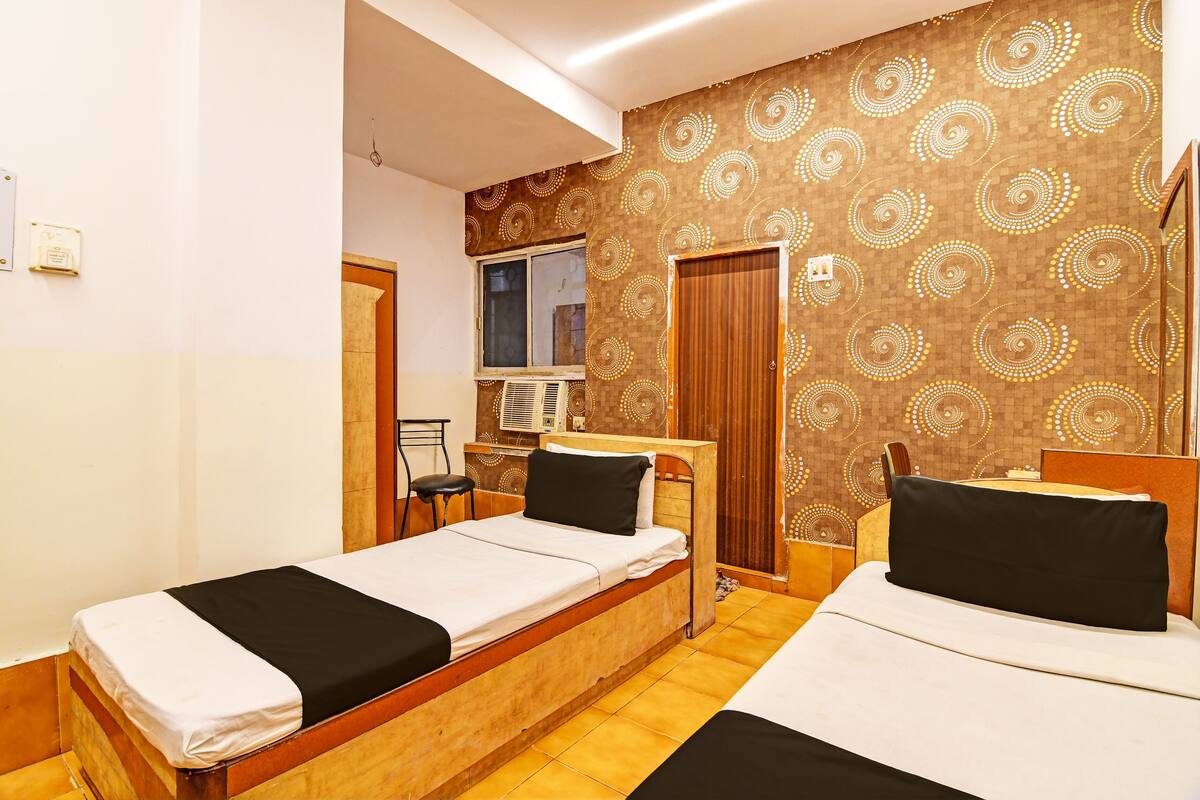 A hotel room with two single beds, a desk, a chair, and a wardrobe.
