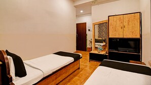 A hotel room with two single beds, a wooden wardrobe, a television, and a mirror. - Hotel Dinar (Kolkata)