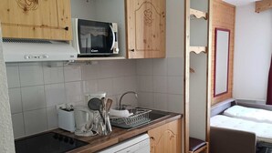Eine kleine Küche mit Holzschränken, einer Mikrowelle, einem Toaster und einem Geschirrspüler.