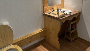 Ein Badezimmer mit einem Holzkosmetikschrank, einem Waschbecken, einem Spiegel und einer Toilette.