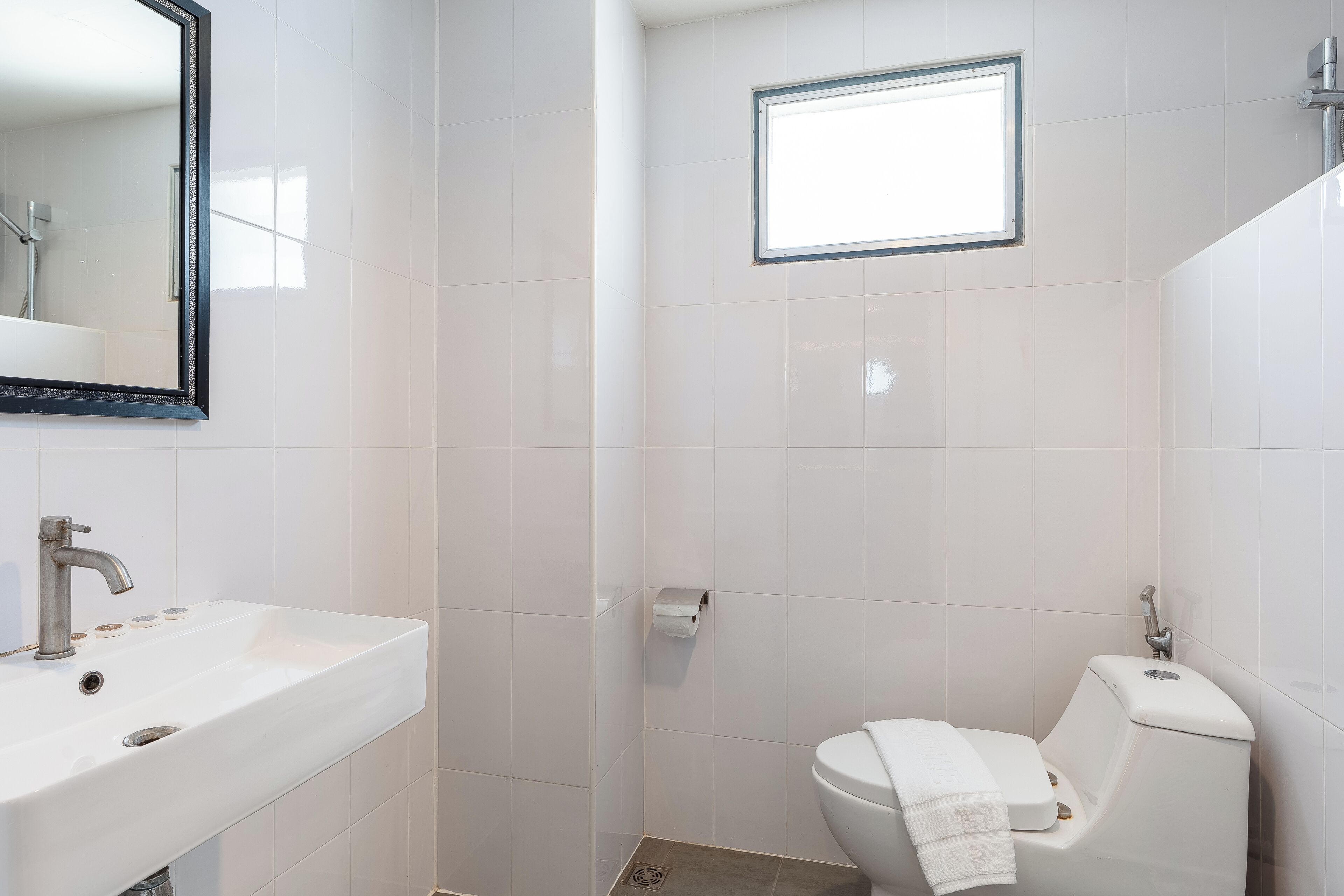 Ein Badezimmer mit Waschbecken, Toilette und einem kleinen Fenster.