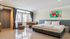 A hotel room with a large bed, a sofa, a small table, and a painting on the wall. - Xanadu Hotel (Ban Chang)