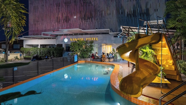 A hotel with a swimming pool, a slide, and a modern building facade. - Xanadu Hotel (Ban Chang)