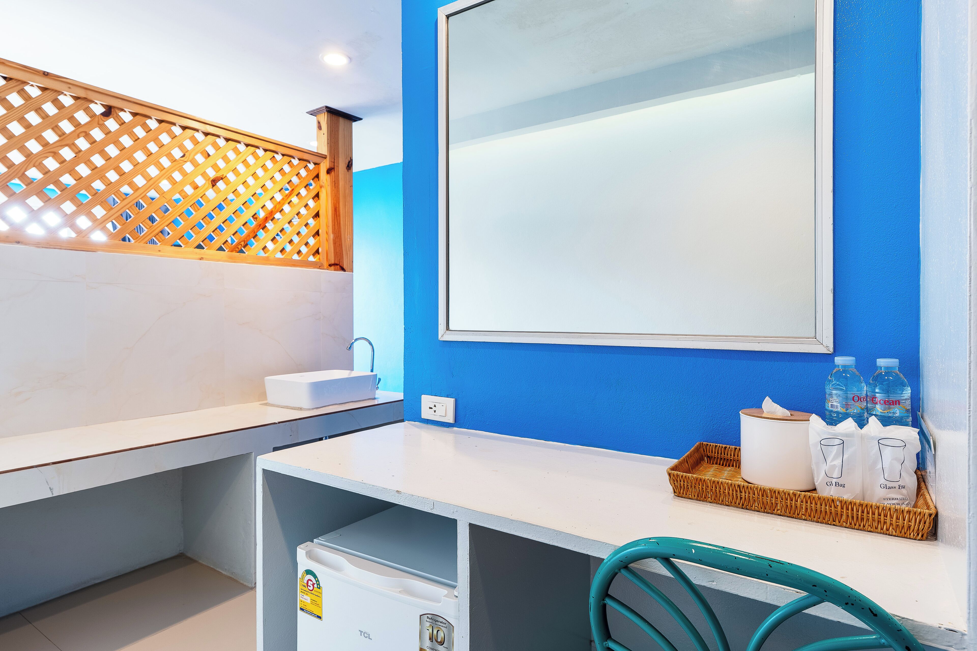 A bathroom with a white sink, a mirror, a blue wall, and a wicker tray with bottles and a tissue box.