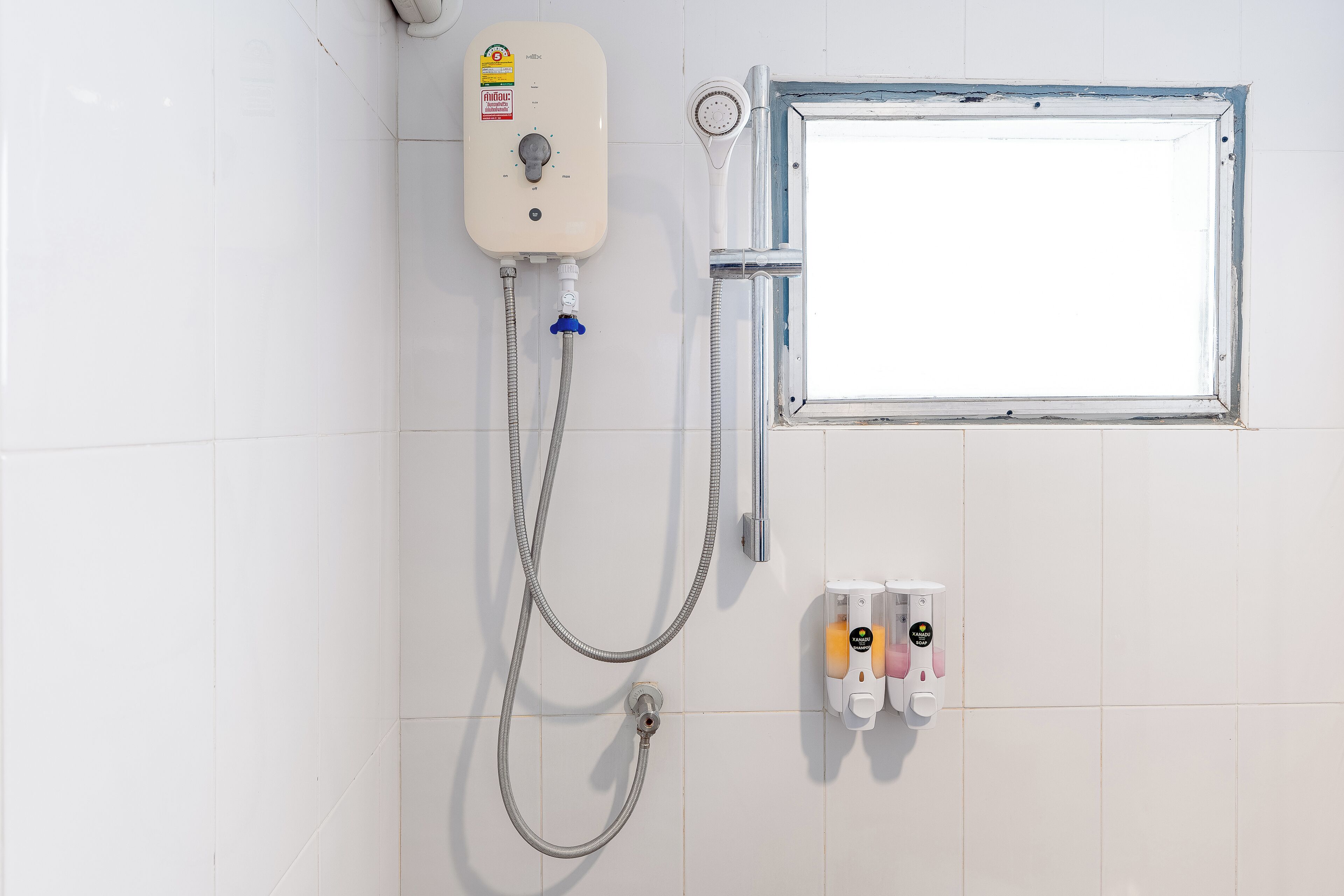 A shower with a control panel, a window, and hand soap dispensers.