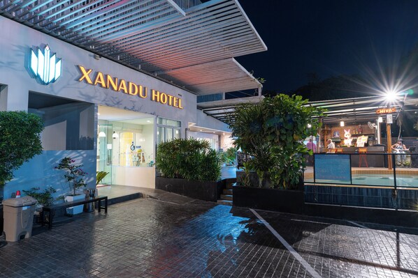The exterior of the Xanadu Hotel with a modern architectural design, featuring a prominent hotel sign, a well-lit entrance, and surrounding greenery.