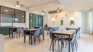 A modern dining area with tables and chairs, ceiling fans, and wall-mounted air conditioning units. - Xanadu Hotel (Ban Chang)
