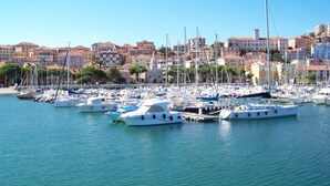 A marina with numerous boats docked, surrounded by buildings with red-tiled roofs.