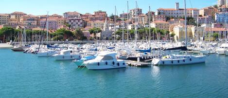 A marina with numerous boats docked, surrounded by buildings with red-tiled roofs.