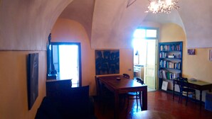 A dining area with a wooden table and chairs, a bookshelf, and a painting on the wall.