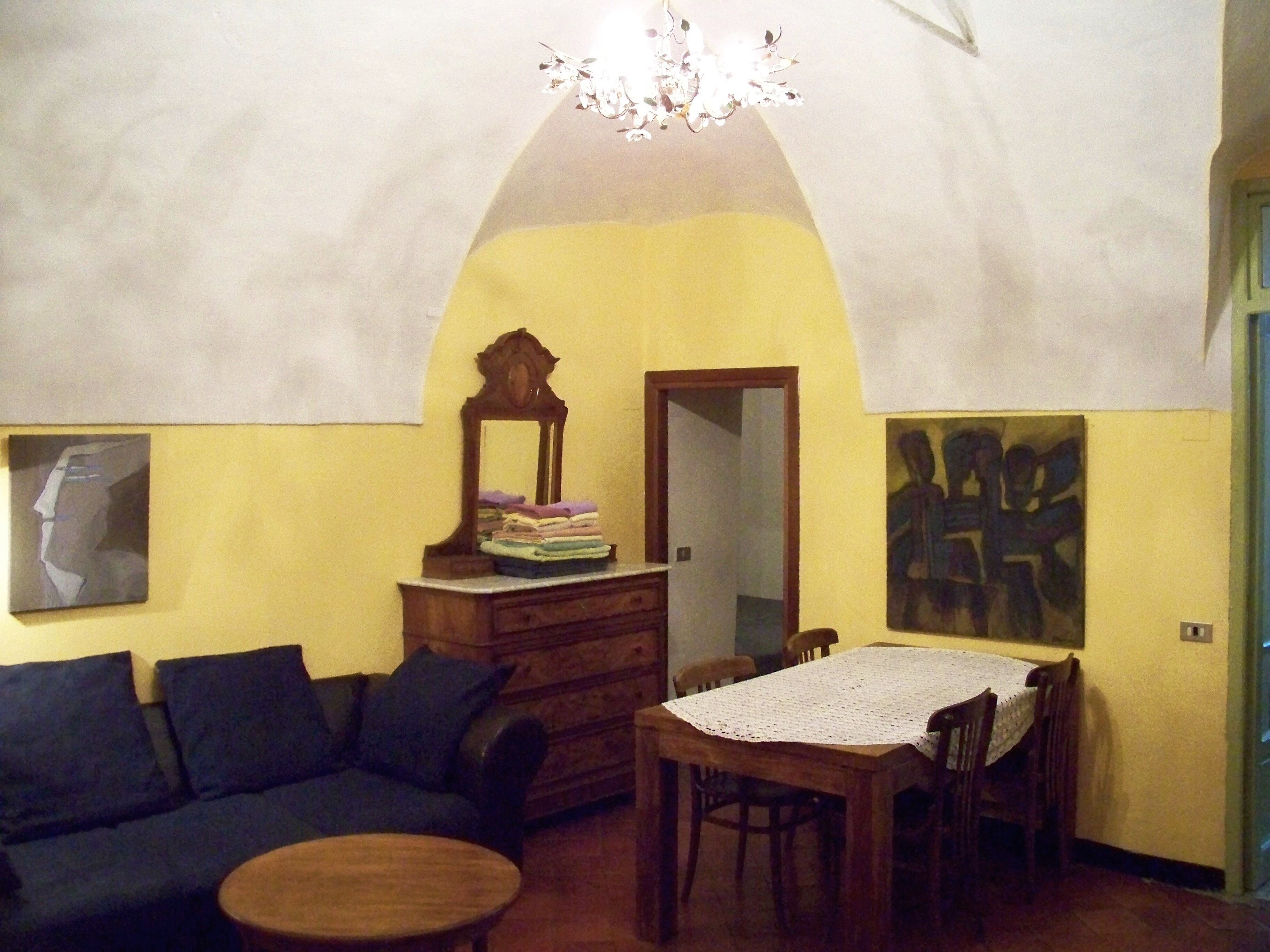 Una stanza con un divano, un tavolo, uno specchio e un quadro appeso al muro.