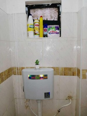 Bathroom features a toilet, water heater, and storage for toiletries.