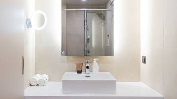 A modern bathroom with a white sink, a mirror, and a towel rack.
