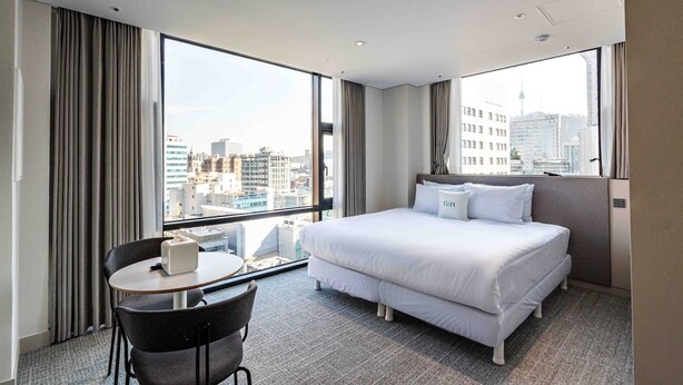 A hotel room with a large window, a bed, a desk, and a chair. - Hotel Vert (Seoul)