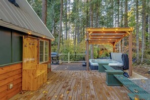 Una baita di legno con veranda, vasca idromassaggio e pergolato con luci decorative.