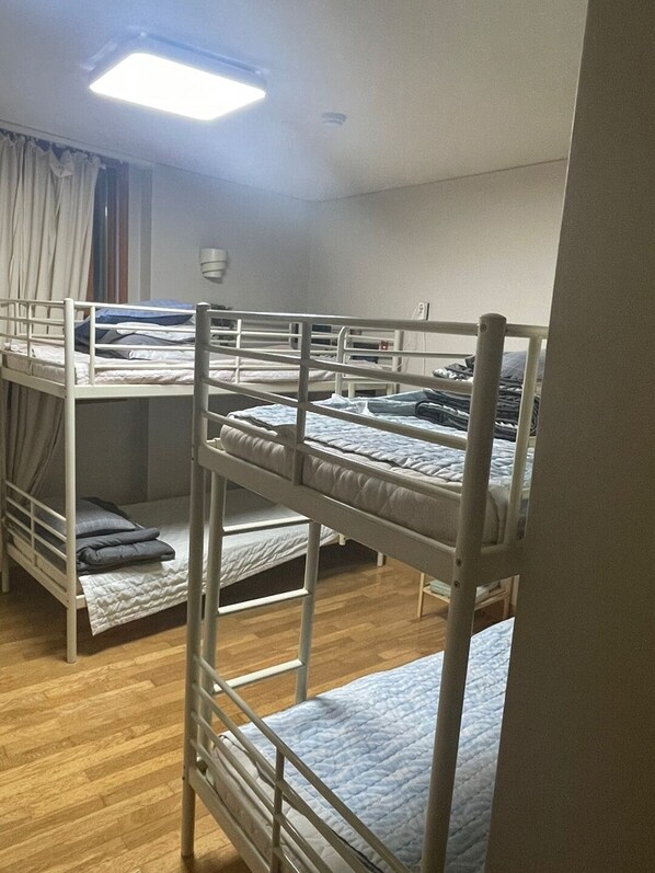 A dormitory room with bunk beds, wooden flooring, and a ceiling light. - Hanra Guesthouse (Jeju City)